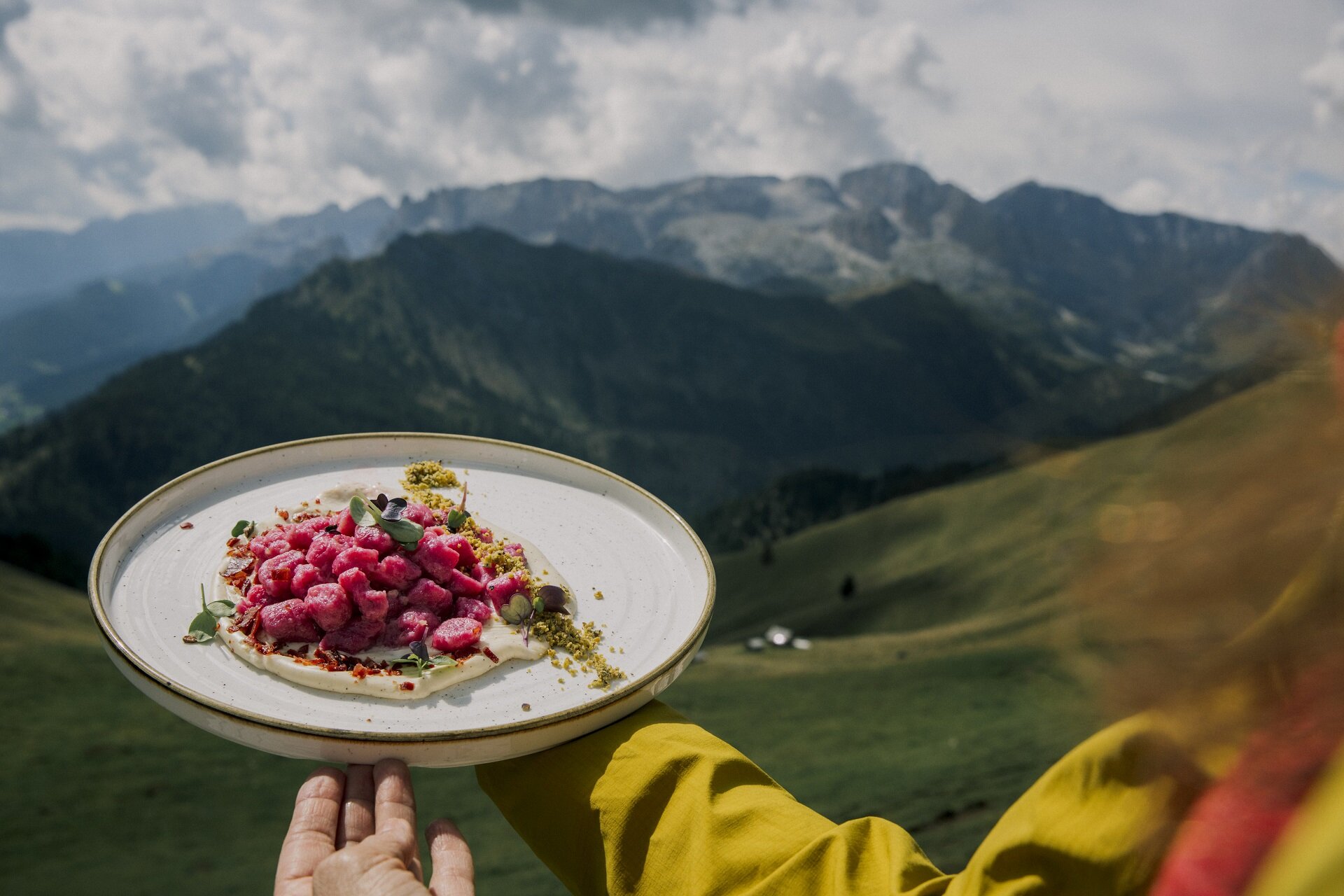 Cucina tipica ad alta quota | © Federico Modica - Archivio Immagini ApT Val di Fassa Piatto di gnocchi rosa da un rifugio con panorama delle Dolomiti di fassa  | © Federico Modica - Archivio Immagini ApT Val di Fassa