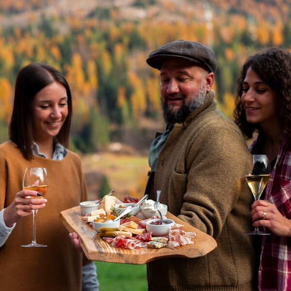 Mangiare e bere in Val di Fassa in autunno | © Archivio Immagini ApT Val di Fassa - Federico Modica  Gruppo di persone assaggia un tagliere di prodotti tipici autunnali della val di Fassa | © Archivio Immagini ApT Val di Fassa - Federico Modica