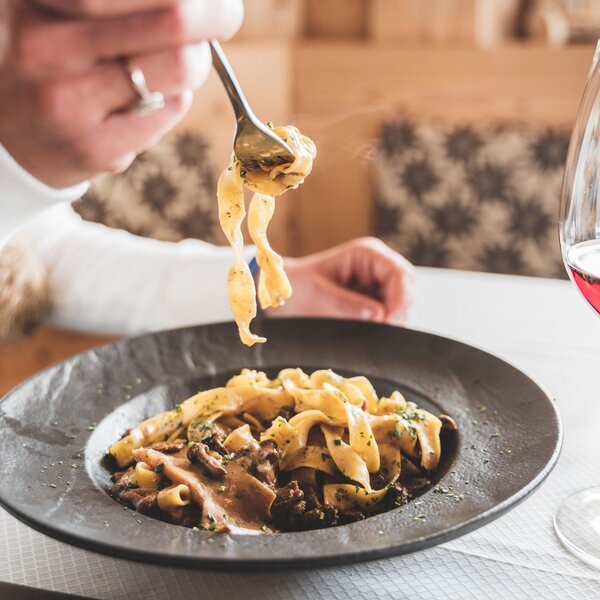 Mangiare al ristorante in Val di Fassa | © Archivio immagini ApT Val di Fassa - Patricia Ramirez Un piatto di tagliatelle ai funghi e un bicchiere | © Archivio immagini ApT Val di Fassa - Patricia Ramirez