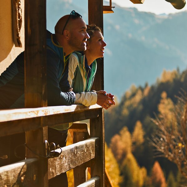 Autunno in Val di Fassa | © Fulvio Maiani Coolpixel - Archivio Immagini APT Val di Fassa Persone che ammirano il paesaggio autunnale da un balcone in legno in Val di Fassa | © Fulvio Maiani Coolpixel - Archivio Immagini APT Val di Fassa
