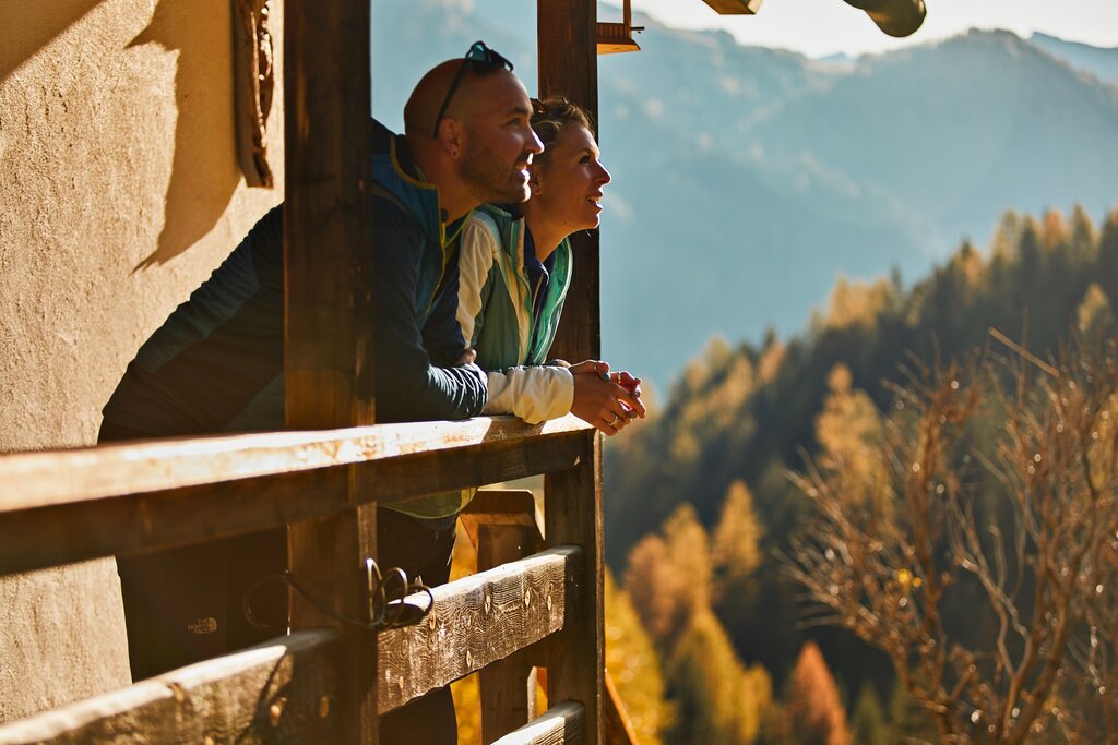 Autunno in Val di Fassa Persone che ammirano il paesaggio autunnale da un balcone in legno in Val di Fassa